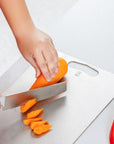 Close-up of a carrot being sliced on a Keith Titanium titanium cutting board on a kitchen counter