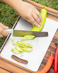 Keith Titanium titanium cutting board being used to slice a green pepper on an outdoor table