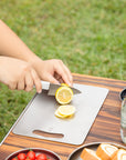 Close-up of hands slicing a lemon on a Keith Titanium titanium cutting board outdoors
