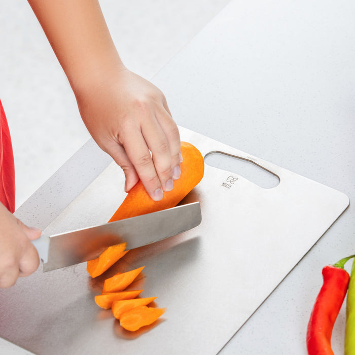 Close-up of a carrot being sliced on a Keith Titanium titanium cutting board on a kitchen counter