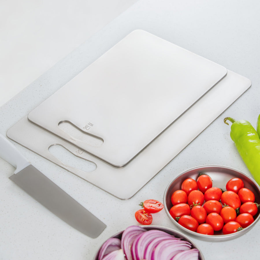 Stacked Keith Titanium titanium cutting boards with a knife and vegetables on a kitchen counter