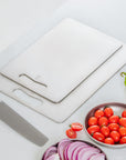 Stacked Keith Titanium titanium cutting boards with a knife and vegetables on a kitchen counter