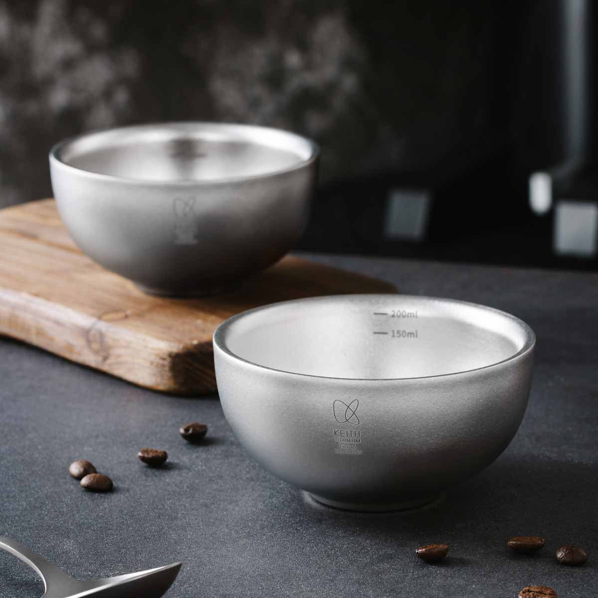 コーヒー豆とともに暗色の卓上に置かれた2個のKEITH Titanium Ti3650カッピングカップ