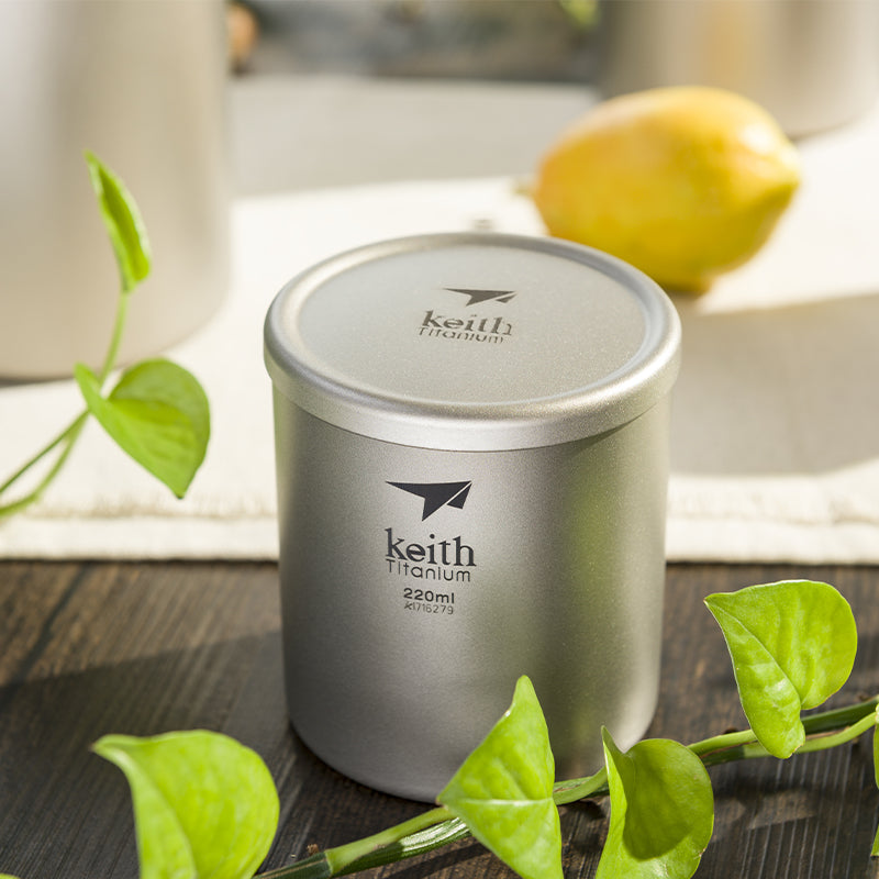 Keith Titanium Ti3301 220 ml double-wall mug on a table among green vines and a lemon