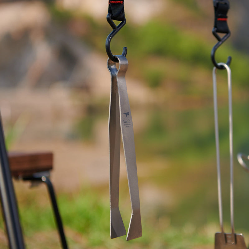 Keith Titanium Ti2206 one-piece tongs hanging from a camp hook outdoors