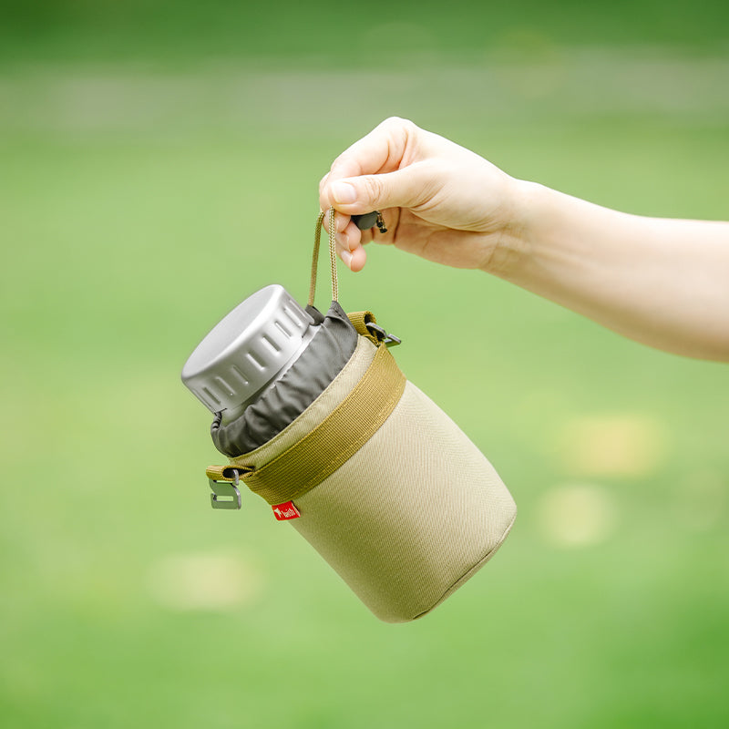 Hand holding the Keith Titanium Ti3035 bottle in its sleeve outdoors