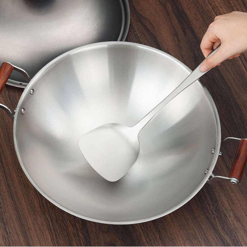 Hand using the Keith Titanium Ti8704 spatula in a wok on a wooden table