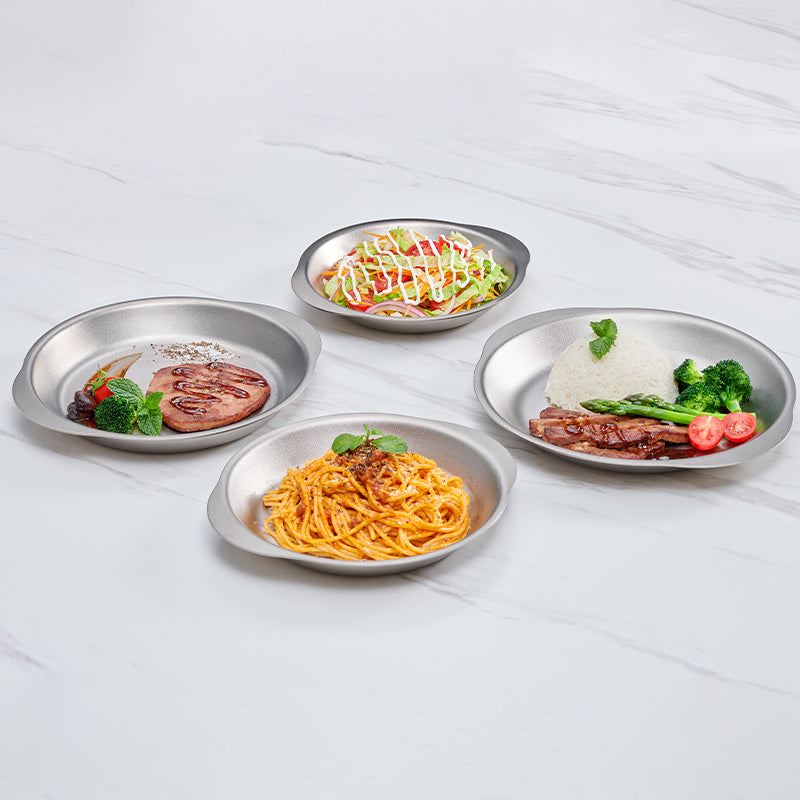 石の背景にサラダ、ライス、ステーキ、パスタを盛った4枚のKEITH Titaniumディナープレート