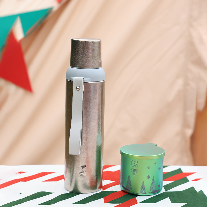 ピクニックテーブルの緑のキャンプカップ横に置かれたKEITH Titanium Ti3106断熱チタンボトル
