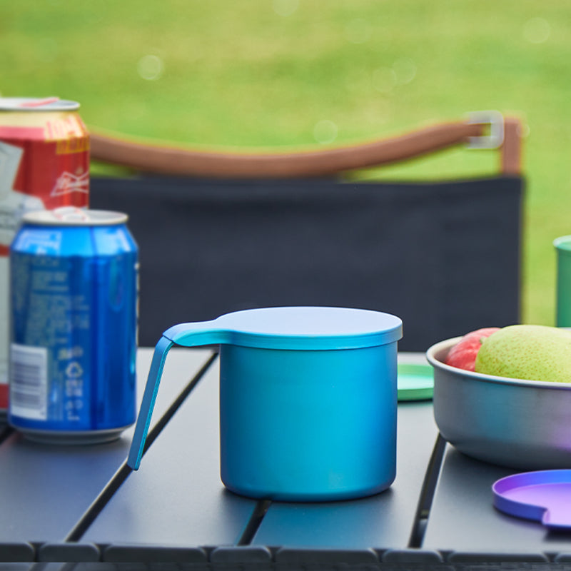 Keith Titanium glacier blue radiant spectrum cup on a camp table beside a drink can and bowl