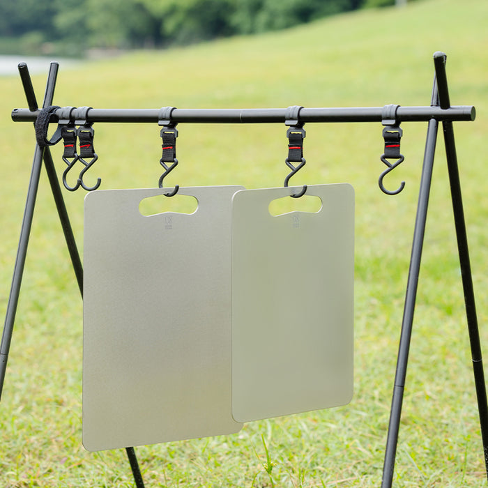 Two Keith Titanium titanium cutting boards hanging from hooks on an outdoor camp rack