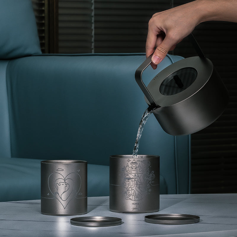 Water being poured into Keith Titanium Jonathan Calugi collectible mugs on a dark table