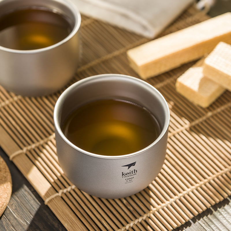 Keith Titanium Ti3906 tea cup filled with tea on a bamboo mat with another cup behind it