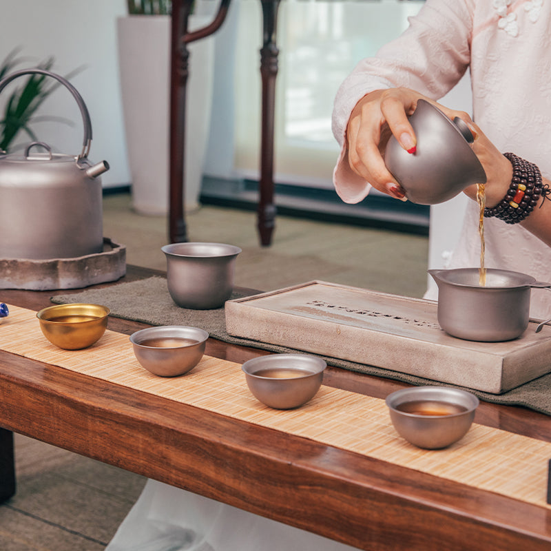 Tea being poured from the lidded pot into the handled pitcher in the Keith Titanium Ti3910 set