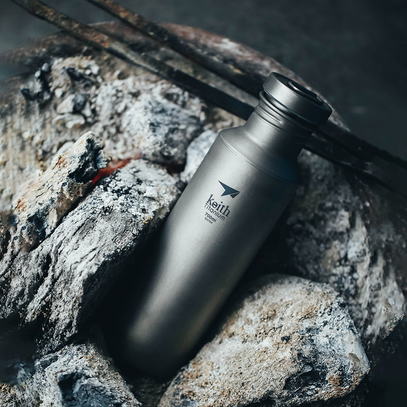 焚き火の残り火のそばに置かれたKEITH Titanium Ti3032チタンスポーツボトル