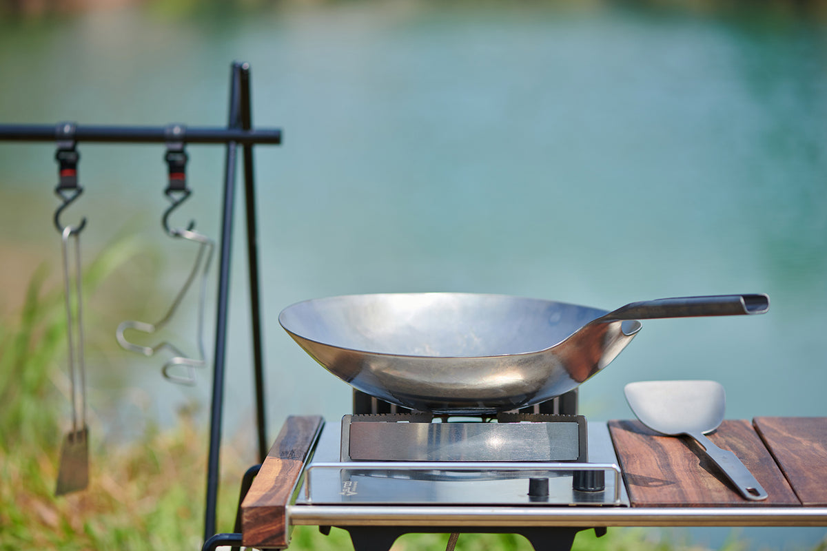 Keith Titanium forged titanium wok on a camp stove beside a lake