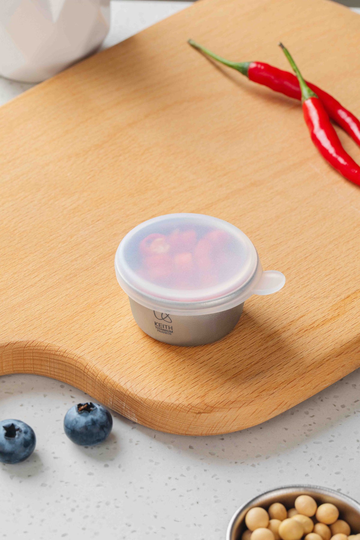 Keith Titanium Ti1161 mini container with chopped red peppers under a translucent lid on a wooden board