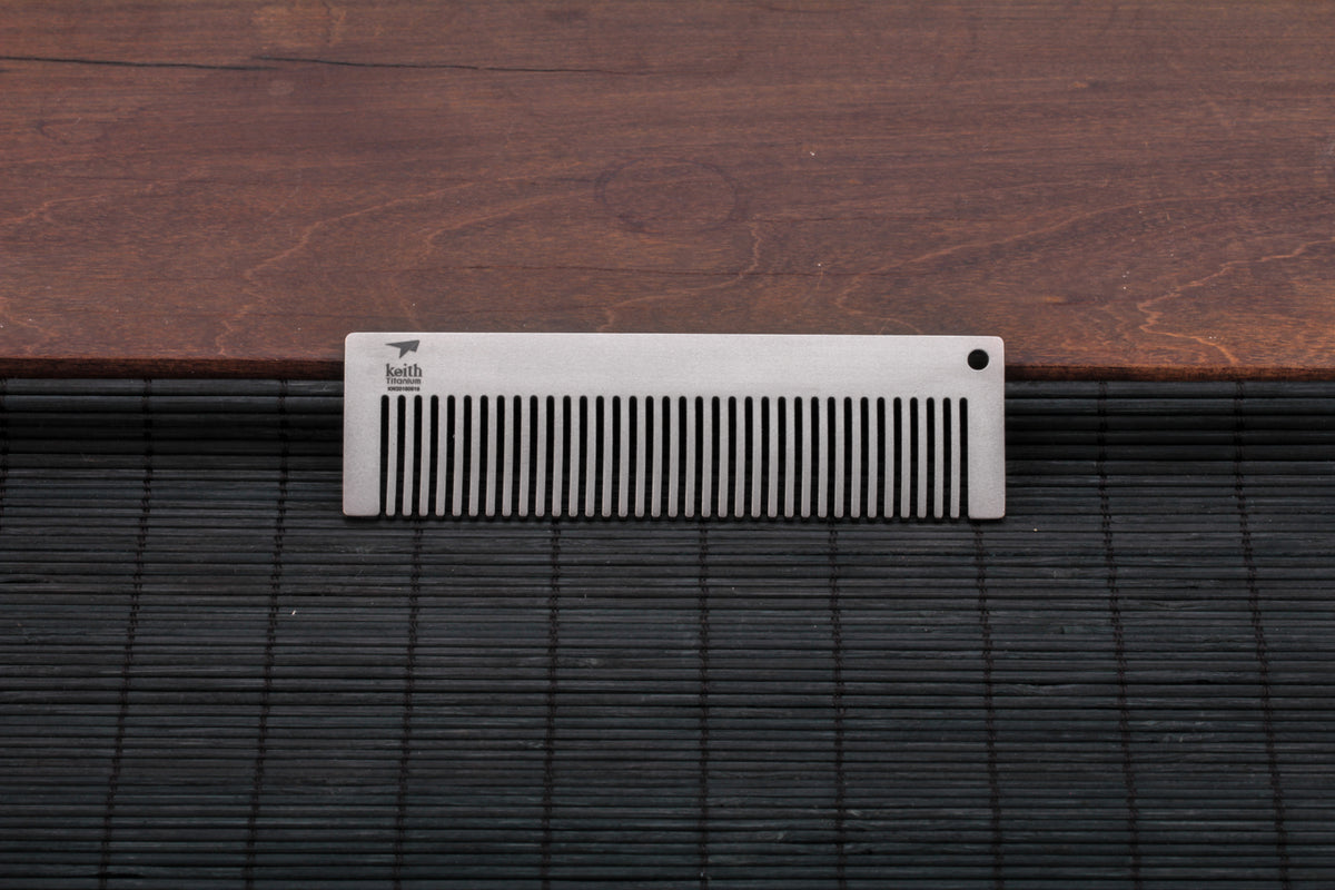 Keith Titanium Ti1732 titanium pocket comb resting on a dark textured surface