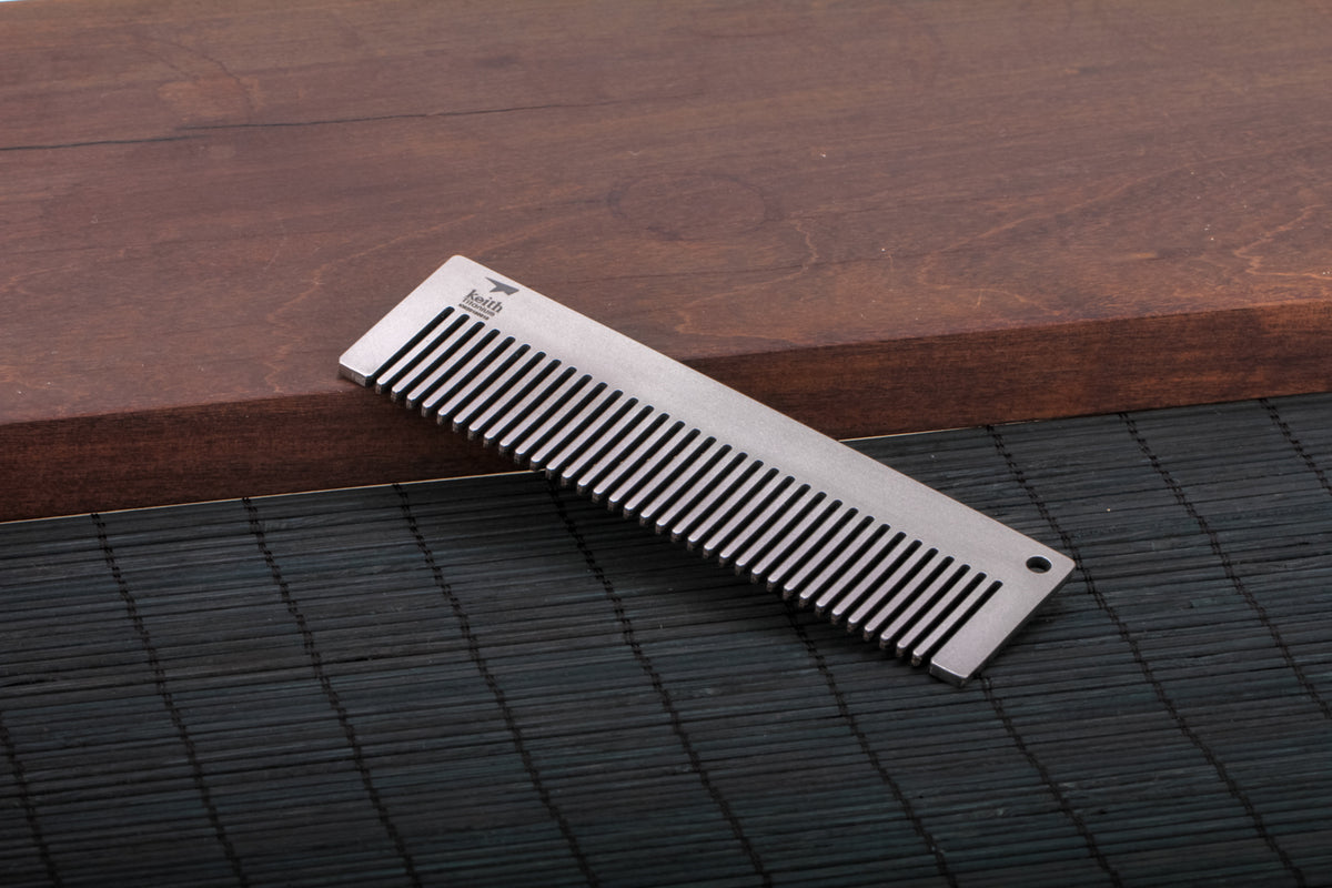 Keith Titanium Ti1732 titanium pocket comb leaning on a dark textured surface
