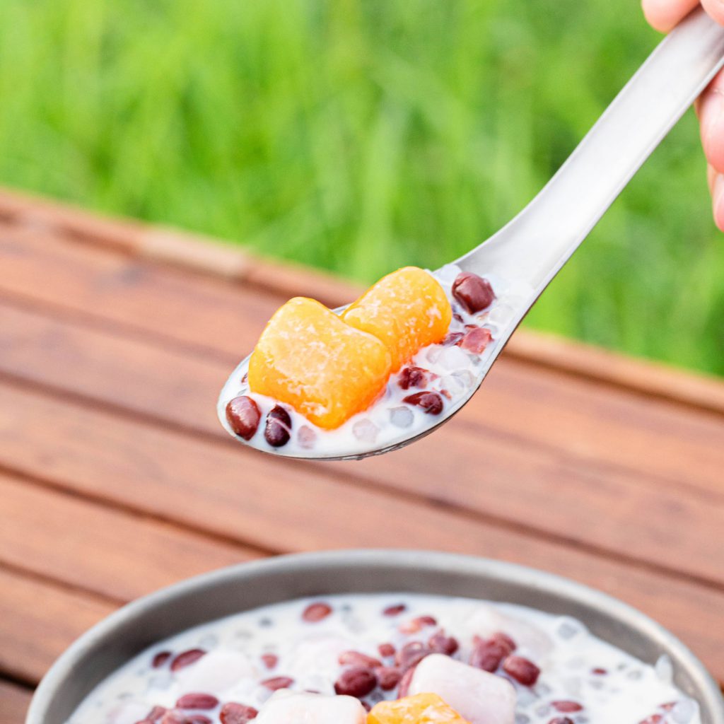 Keith Titanium Ti5316 small spoon holding dessert above a bowl on a wooden table