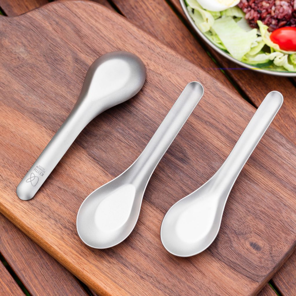 Three Keith Titanium small spoons of the same size on a wooden table