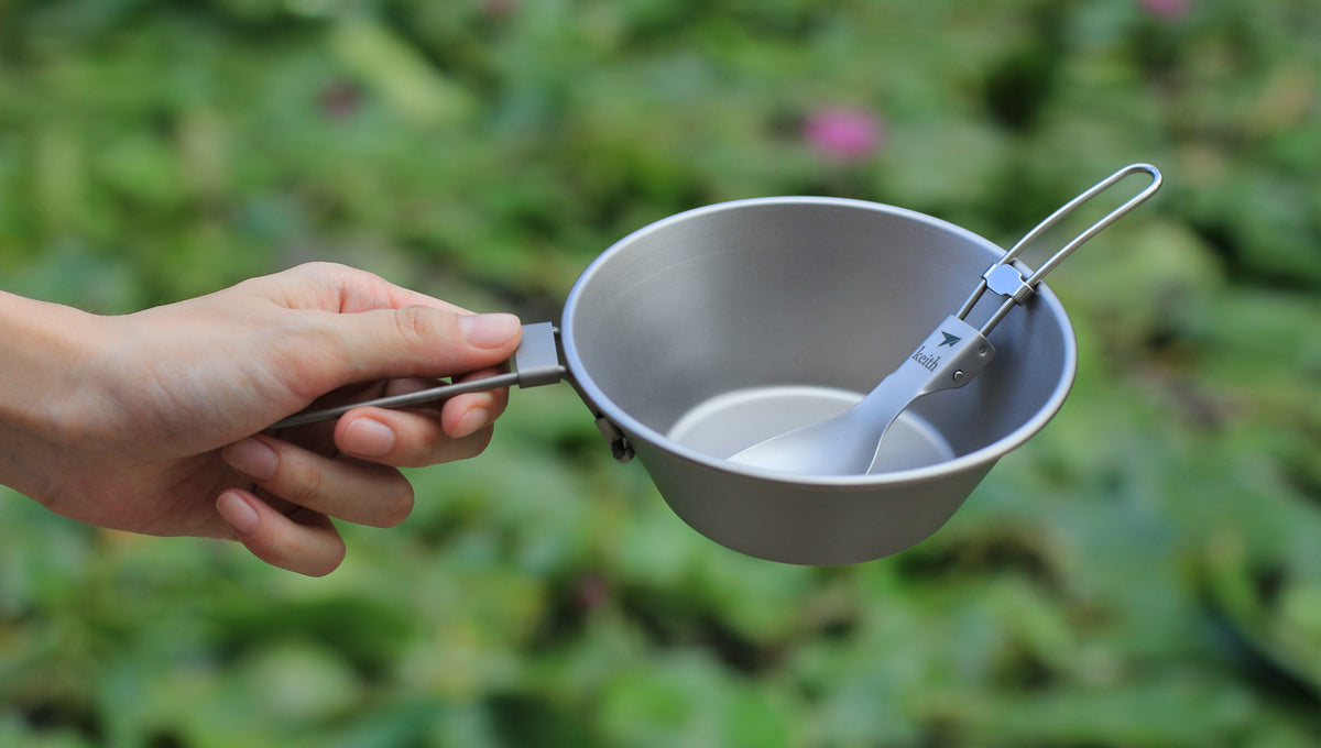 Hand holding the Keith Titanium Ti5320 bowl with a spoon and fork inside