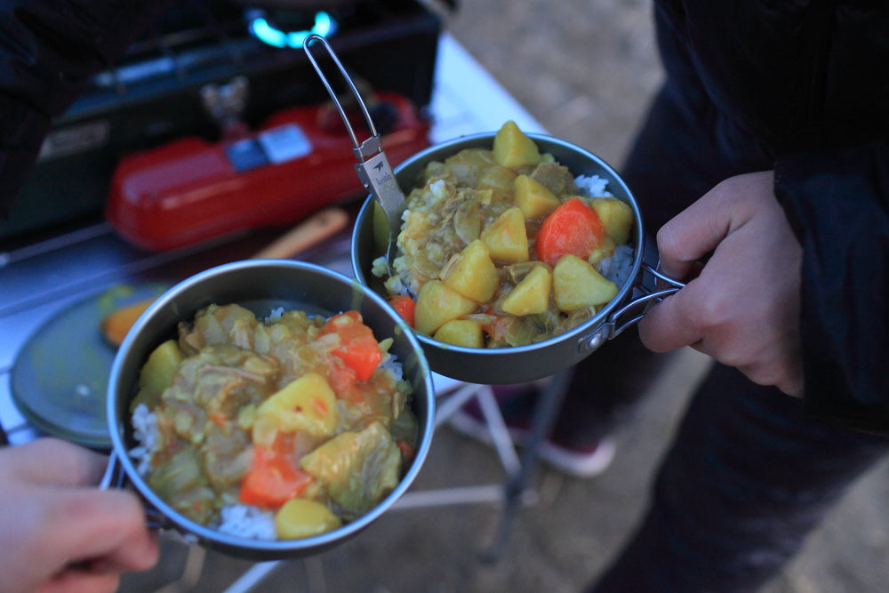 屋外でカレーとご飯を入れたKEITH Titaniumボウルを両手で持っている様子