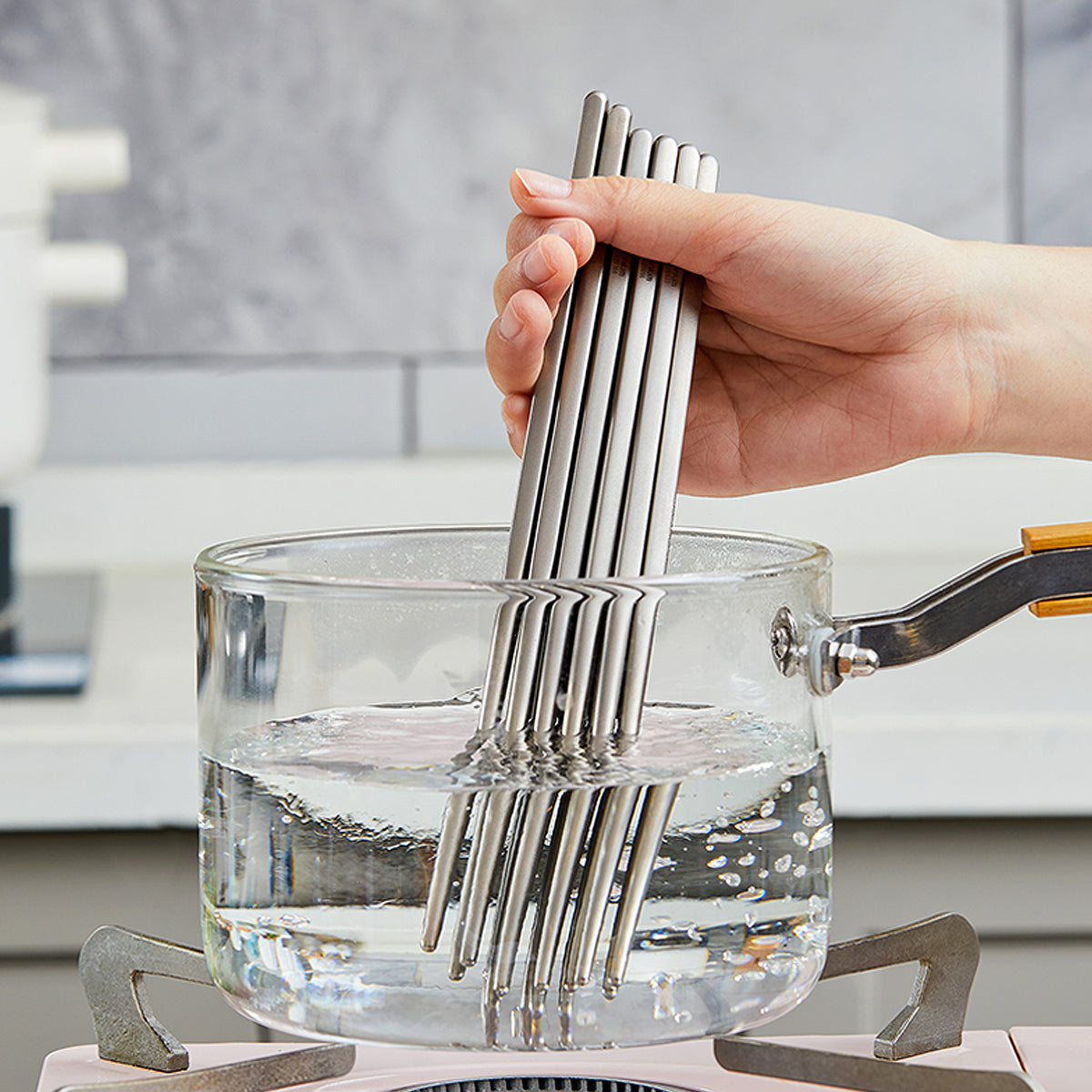 Hand rinsing several pairs of titanium chopsticks in a pot of water